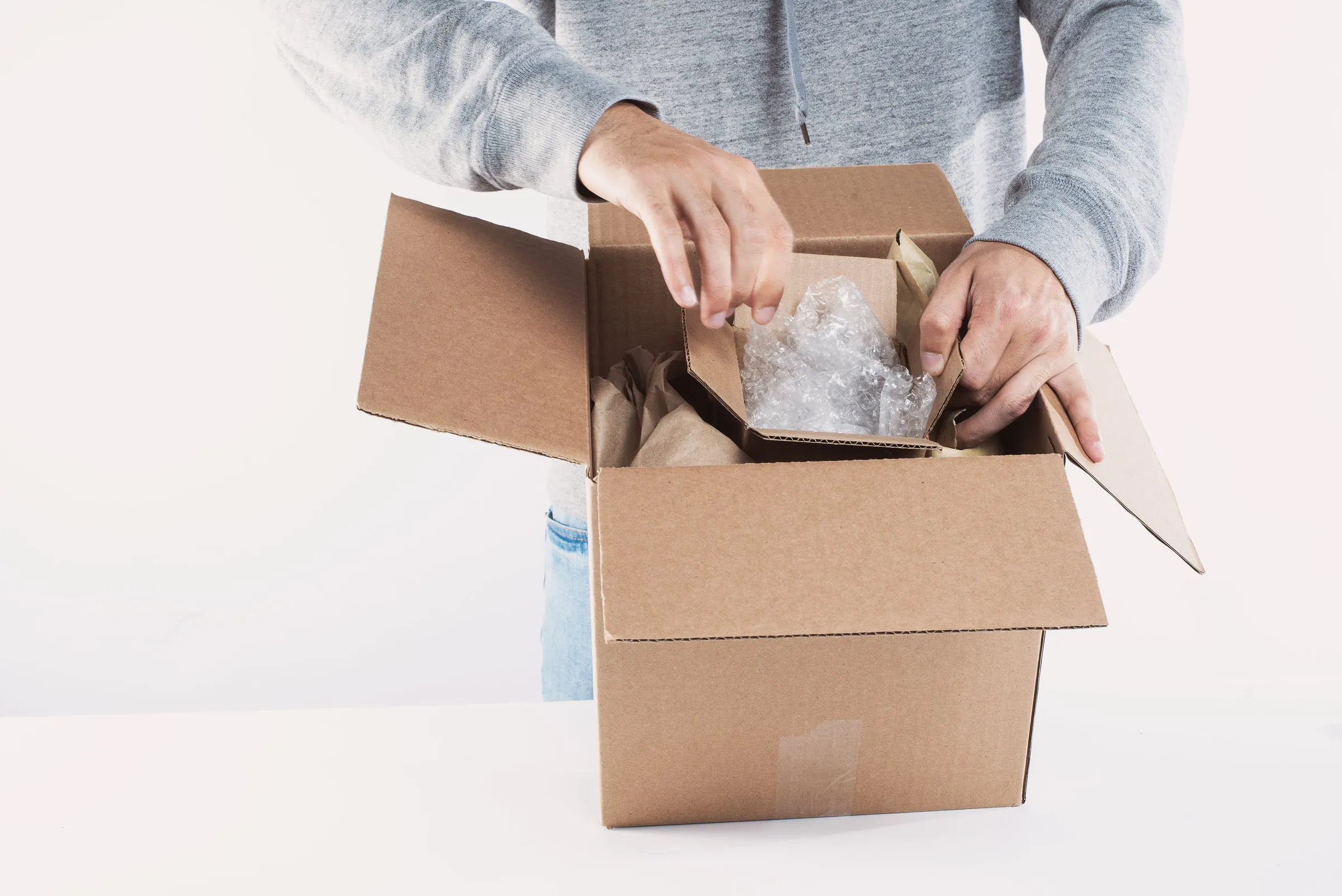 A person packing an online order into a cardboard box